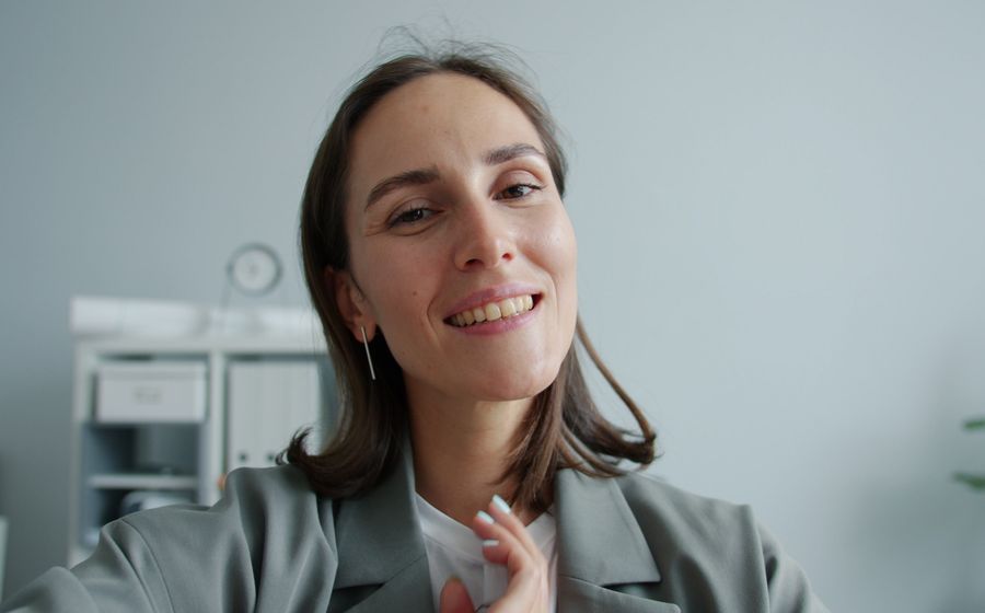Smiling learner waving during a video assessment